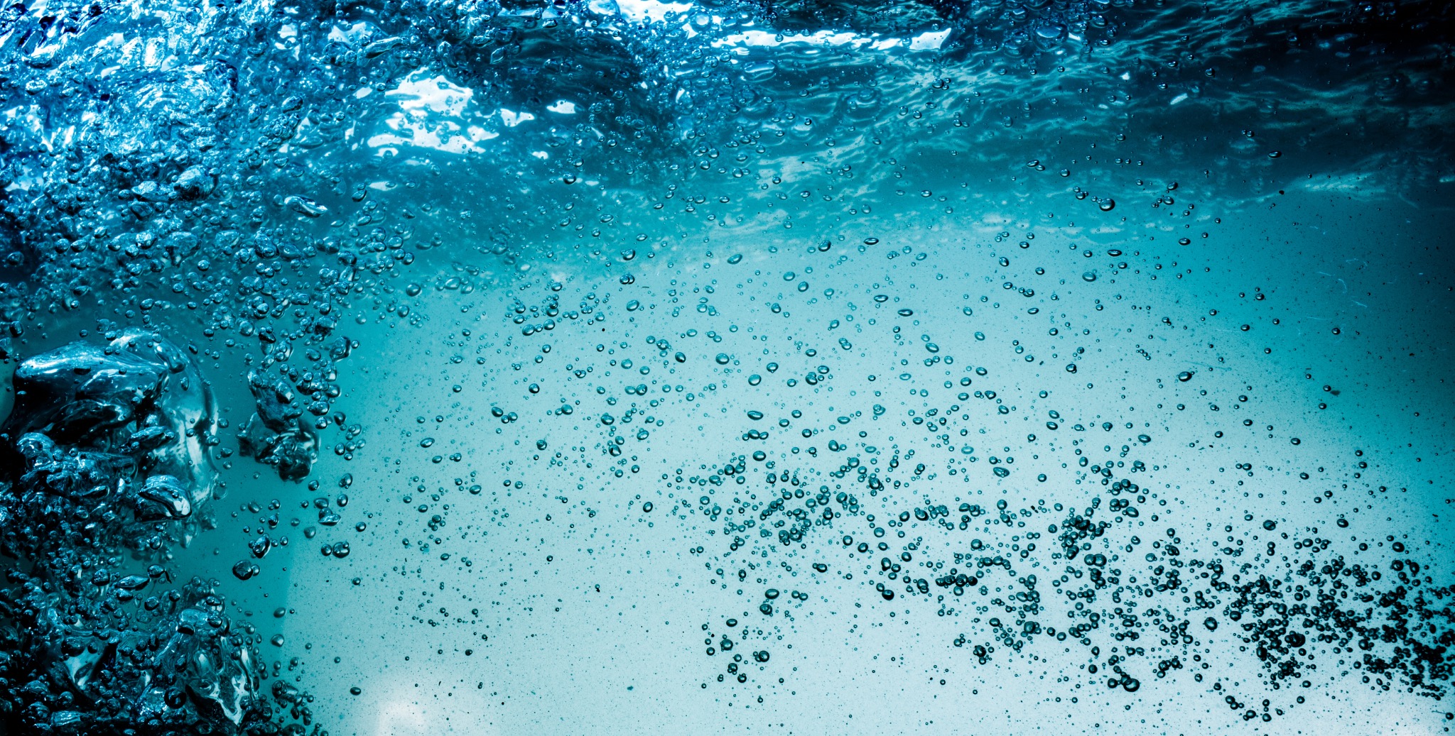 Air bubbles rising through clear blue water.